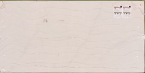 Large rectangular slab of light gray stone with subtle wavy vein patterns and labels in the top right corner.